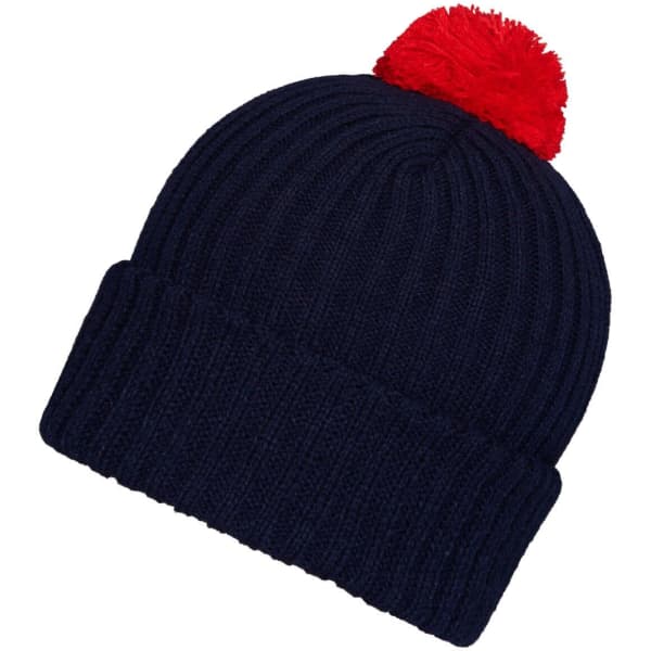 A navy knitted beanie with a red pompon on top and a ribbed design. The beanie includes a branding logo.