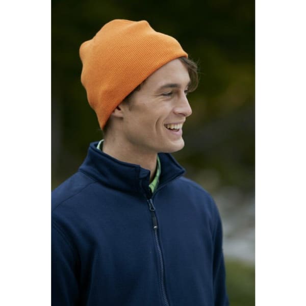 An orange beanie worn by a smiling man dressed in a navy jacket, set against a natural backdrop.