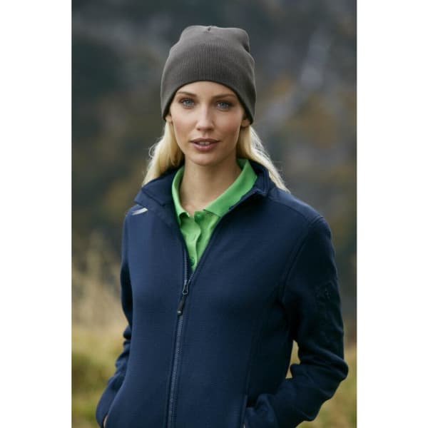 A woman wearing a grey cotton beanie and a navy jacket, standing outdoors with a blurred natural background.