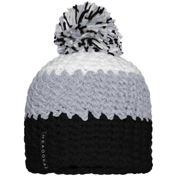 A knitted beanie featuring a pompon, in shades of grey, white, and black, with a logo tag.