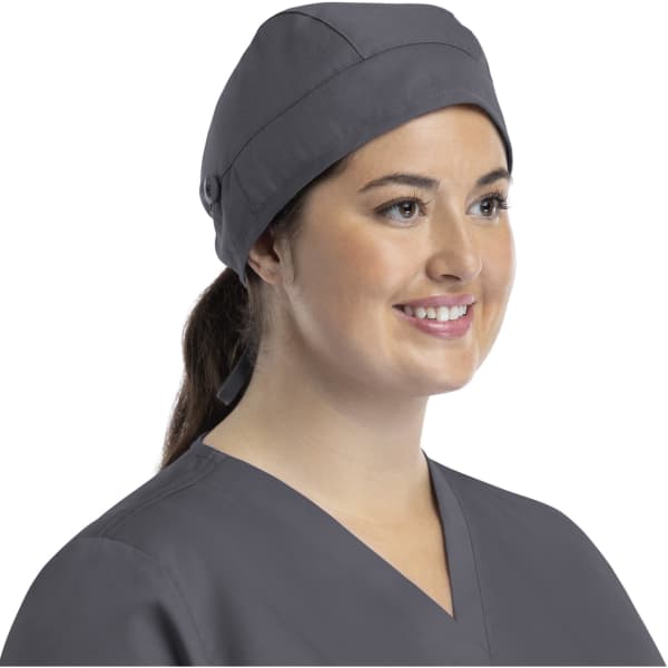 A grey cap with a button, worn by a smiling woman in a grey top, showcasing a stylish design.