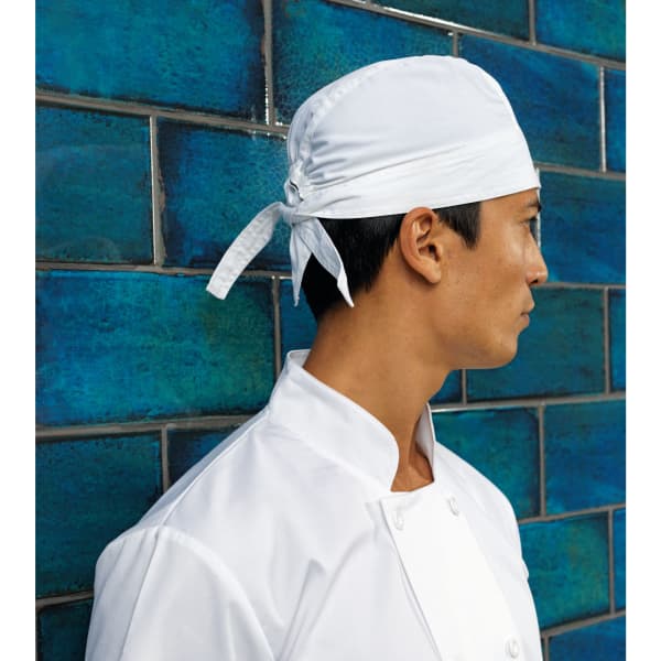 A white chef's zandana worn by a man in a white chef's jacket, against a blue tiled wall.