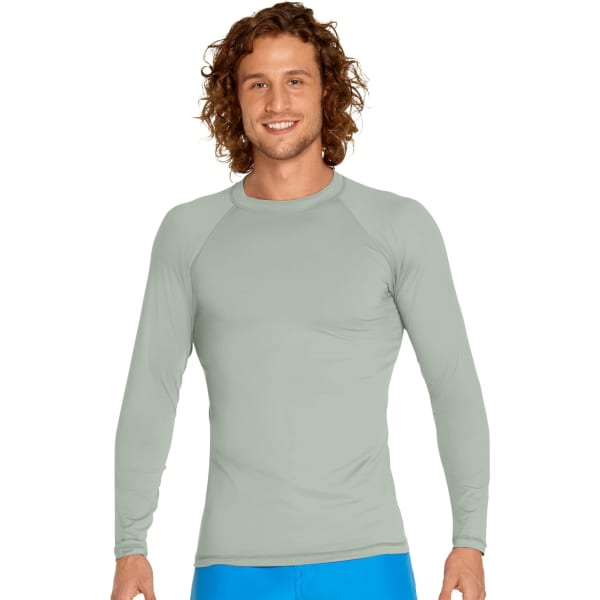 A man wears a light green long sleeve rash guard with a fitted design. The garment features a logo.