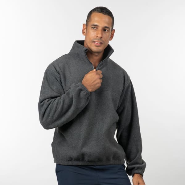 A man models a charcoal grey 1/4 zip polar fleece pullover with a logo on the chest.