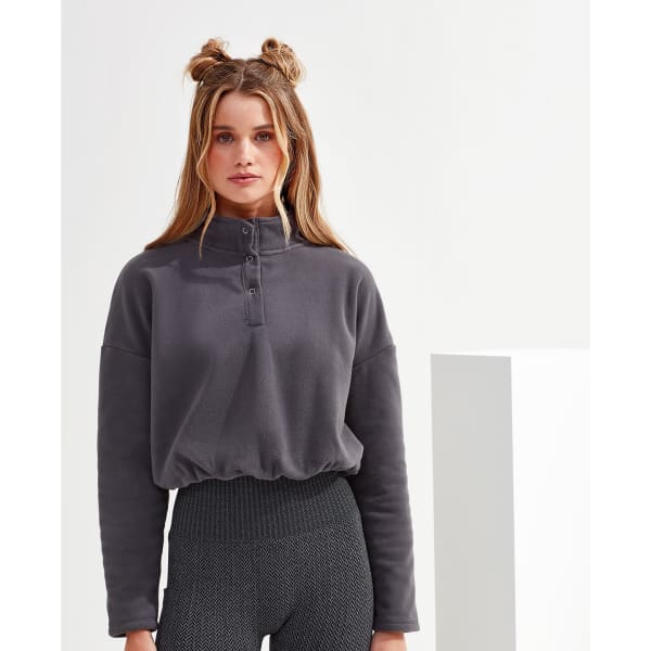 A grey cropped fleece top with a high collar and button detailing, paired with textured, high-waisted leggings.