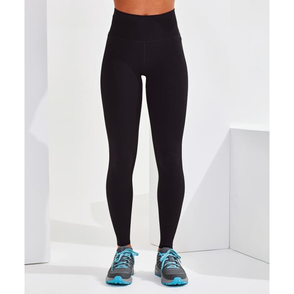 A pair of black seamless leggings displayed on a model, paired with grey and blue athletic shoes.