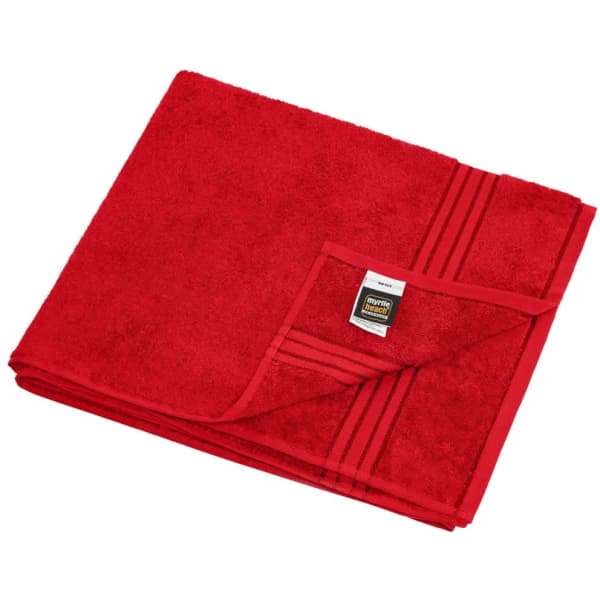 A red sauna sheet neatly folded, featuring a textured surface and a branded label on the corner.