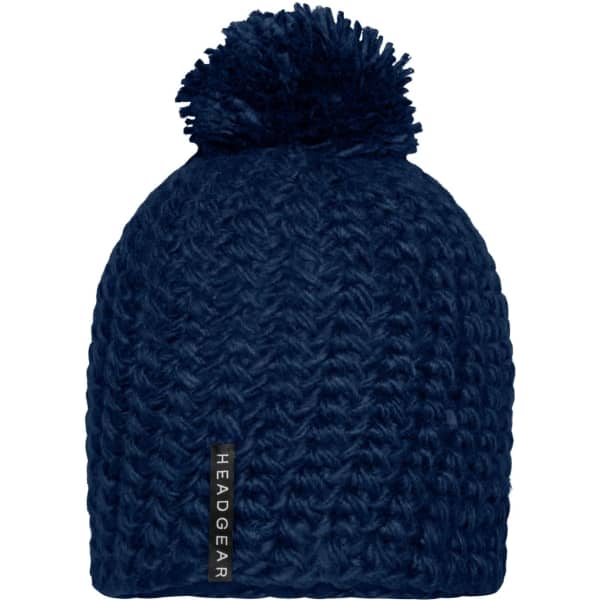 A unicoloured navy crocheted cap with a fluffy pompon on top and a logo label on the side.