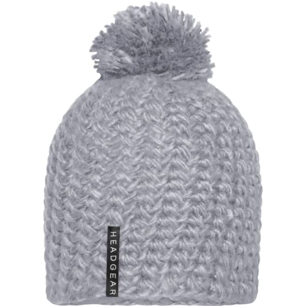 A grey crocheted cap with a textured pattern and a fluffy pompon on top. The cap features a branding label.