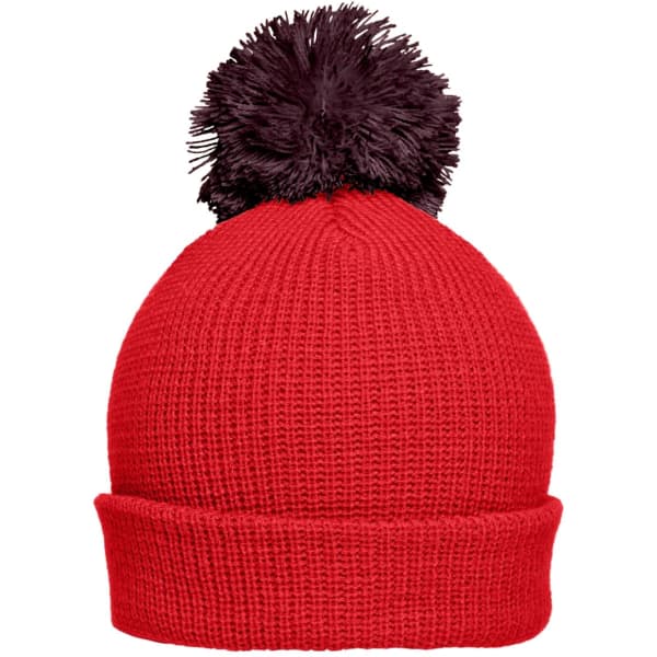 A bright red beanie hat with a black pompon on top, featuring a ribbed texture. It has a fold-over brim and a logo.