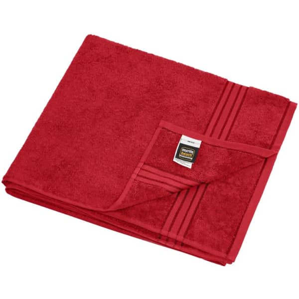 A folded red sauna sheet with a textured surface, featuring a folded edge and a small tag with branding.