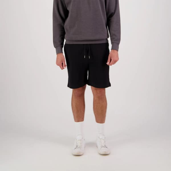 Black sports shorts with a drawstring waist, modelled with a grey sweatshirt and white socks and shoes. Features a logo.