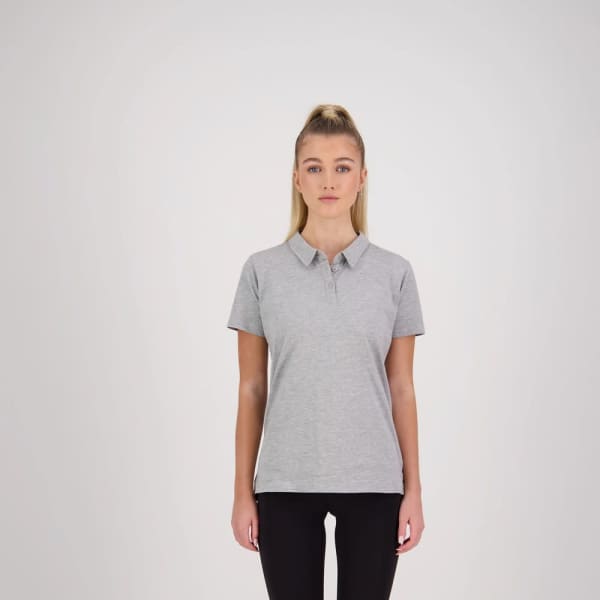 A woman wearing a light grey polo shirt stands against a plain background. The shirt has a collar and short sleeves.