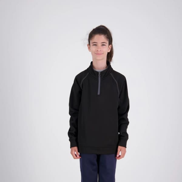 A girl wearing a black XT Performance Drill Top, featuring a zip collar and a logo.