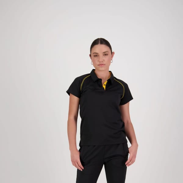 A women's black polo shirt with yellow accents and a logo. The model is standing confidently in a neutral background.