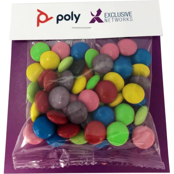 A clear bag filled with brightly coloured choc beans, including green, pink, yellow, and purple, on a branded backing.