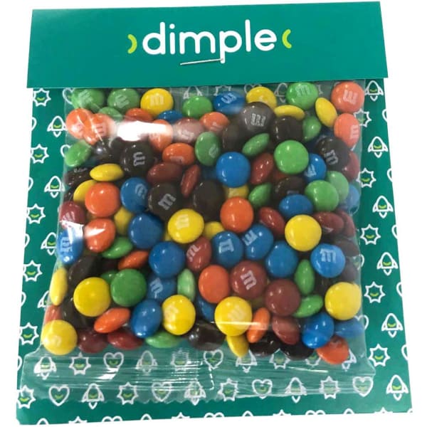 A bag of colourful M&M chocolates in various shades including red, blue, green, orange, and brown, with branding.