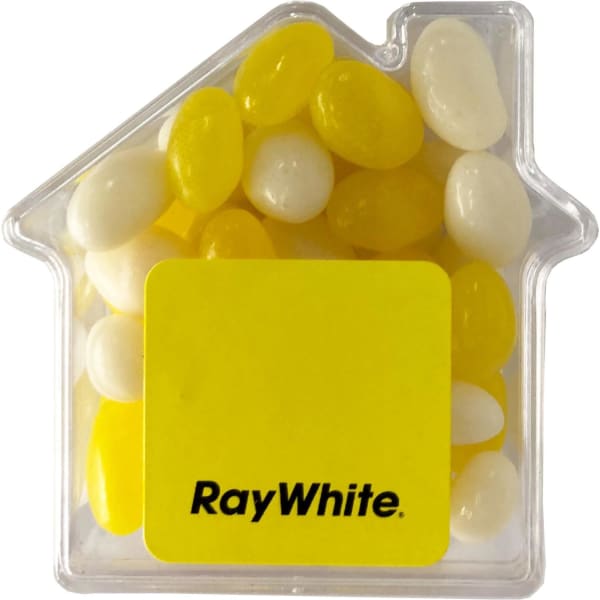 A clear acrylic house-shaped container filled with yellow and white jelly beans. It features a logo on the front.