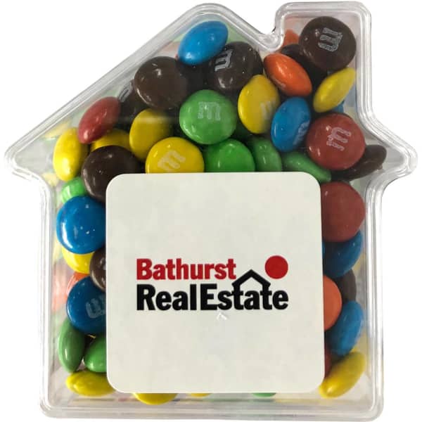 A clear acrylic house filled with colourful M&Ms in various shades of blue, green, red, yellow, and brown.