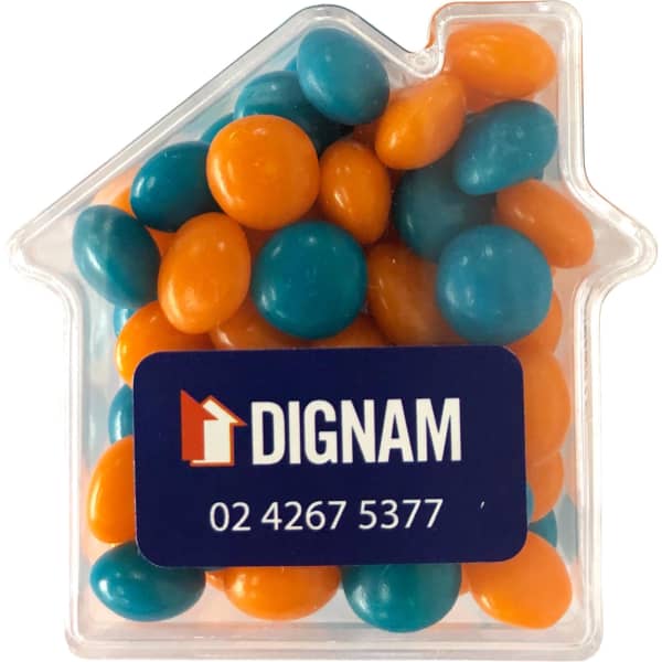 A clear acrylic house-shaped container filled with orange and teal chewy fruit candies. Features a logo.