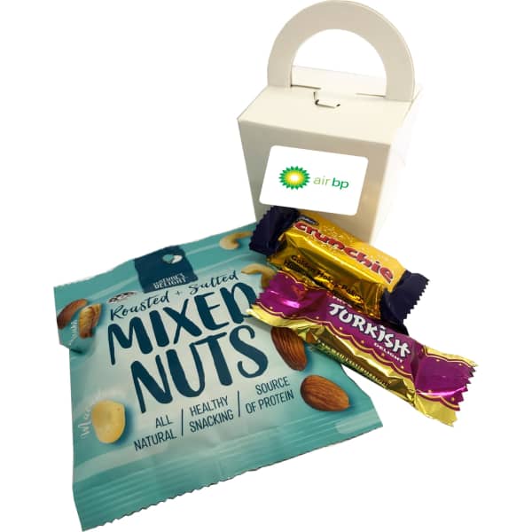 A white takeout box with mixed nuts, a chocolate bar, and a Turkish Delight in purple and gold wrappers.