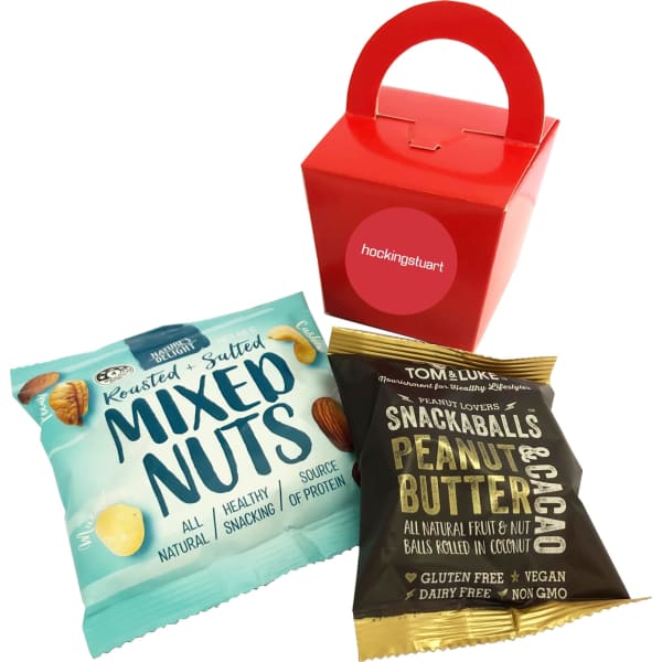 A red noodle box contains a packet of mixed nuts and a snack ball pack in brown and blue packaging.