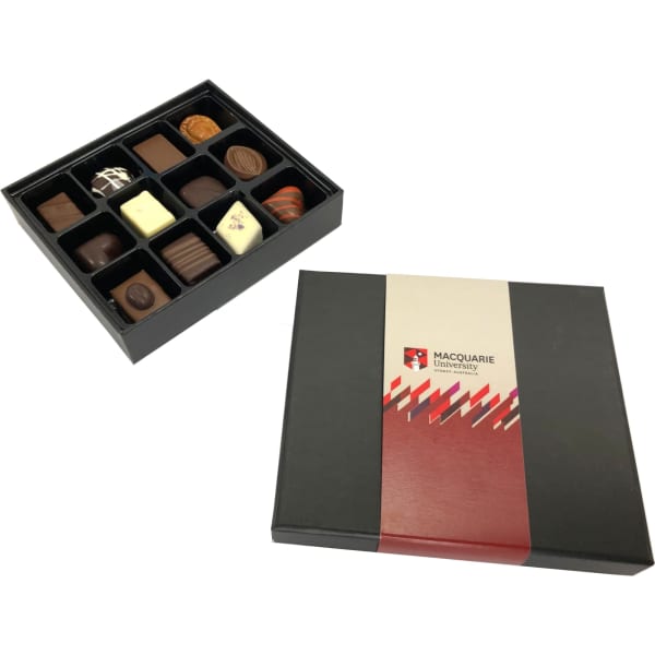 A black box containing an assortment of praline chocolates in various shapes and colours. The box has a logo.