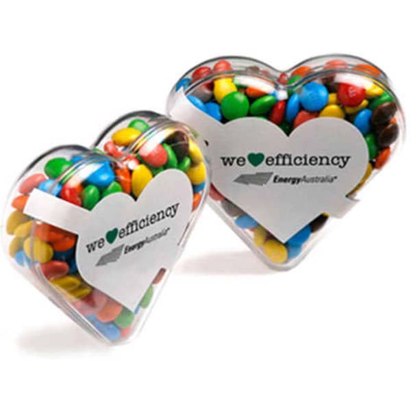 Acrylic heart-shaped container filled with colourful M&Ms, featuring a logo on the front.