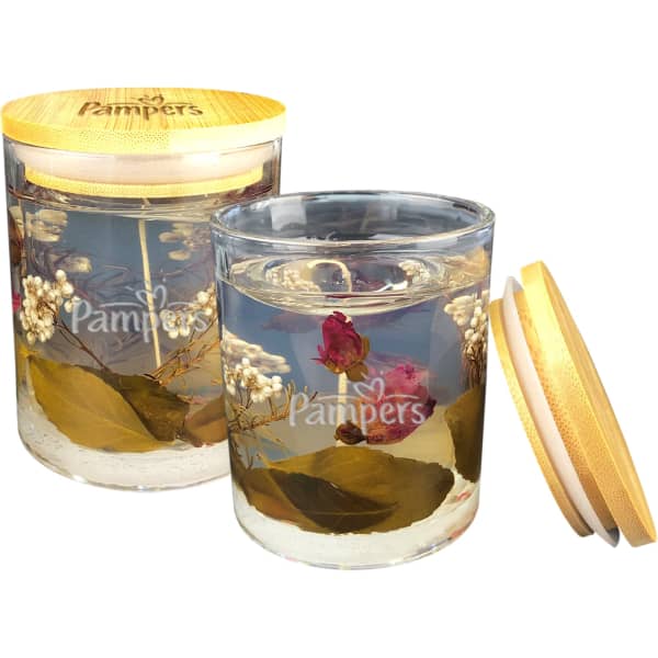 A floral candle in a glass jar, filled with preserved flowers and greenery, featuring a wooden lid.