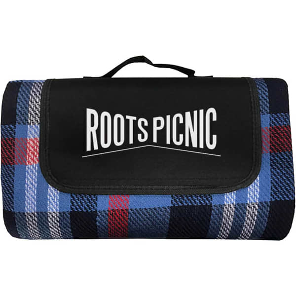A picnic blanket featuring a navy, red, and grey plaid pattern, with a black carrying handle and logo.