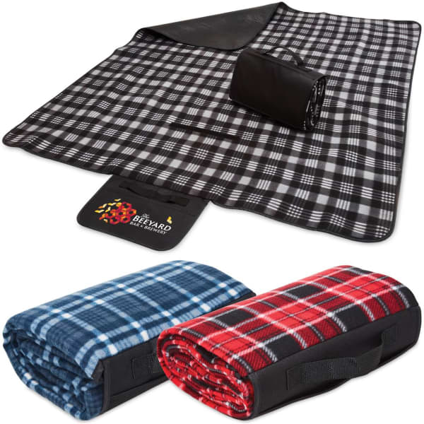 A black and white checkered picnic rug, rolled up with a black strap, alongside blue and red patterned blankets.