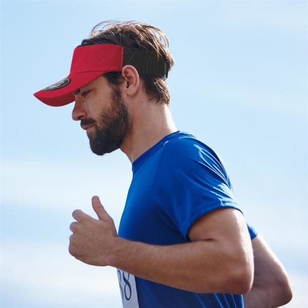 A red sports visor worn by a man in a blue shirt, with a logo visible on the visor.