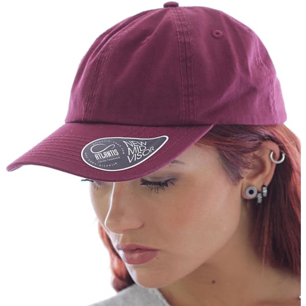 A maroon Dad Hat with a curved visor and a logo on the side, worn by a person with red hair.