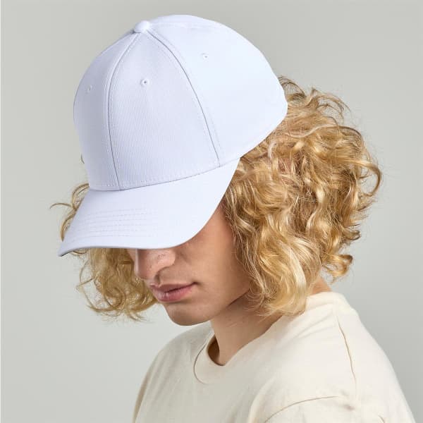 A white cap with a curved brim and a structured fit, worn by a person with curly hair. It features a logo on the front.
