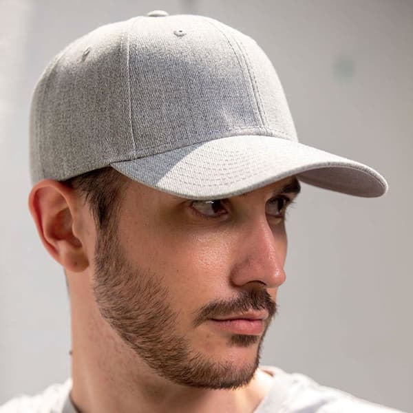 A grey cap with a curved brim, featuring a stitching pattern along the panels and a logo on the front.