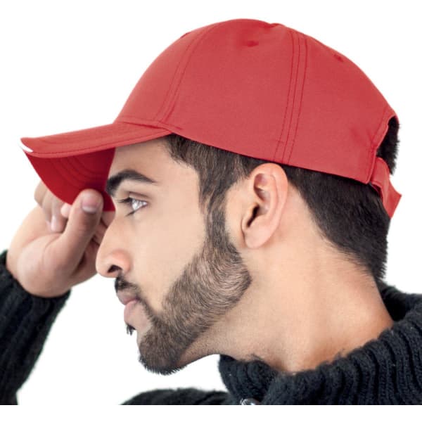 A red cap viewed from the side, featuring a curved brim and an adjustable strap at the back.