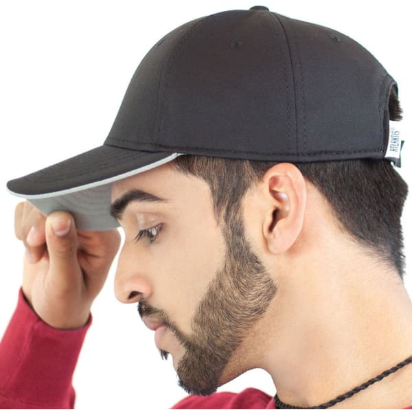 A black cap with a contrasting under-peak, featuring a logo and worn by a model.