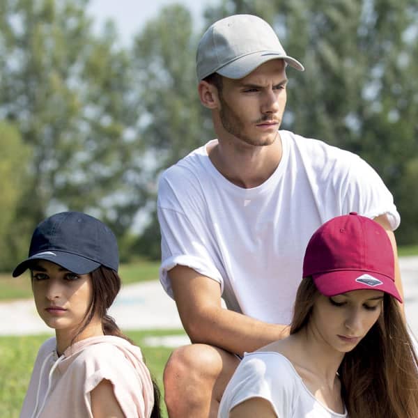 A trio of individuals wearing caps in various colours: navy, burgundy, and a light grey cap, all featuring logos.