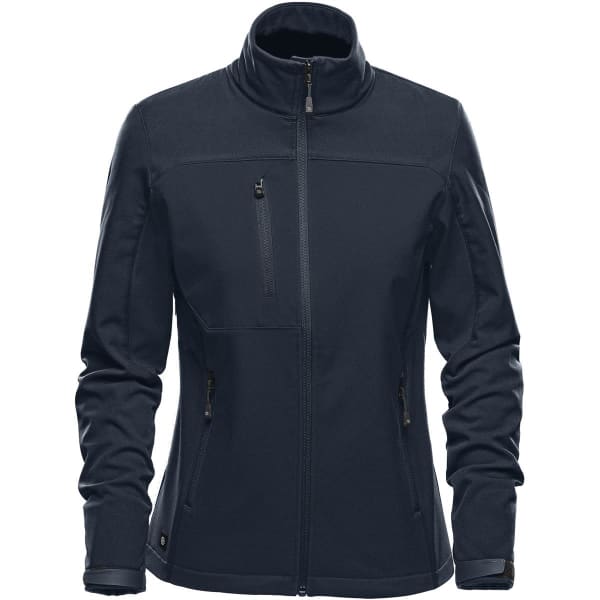 A women's softshell jacket in navy blue featuring a stand collar and multiple zippered pockets. It has a logo on it.