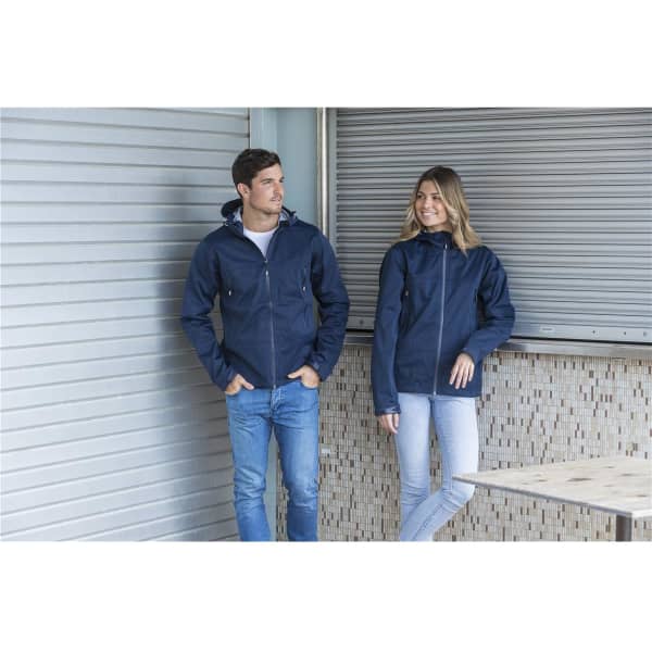 A navy unisex shell jacket with a hood is worn by both a male and female model, featuring a logo.