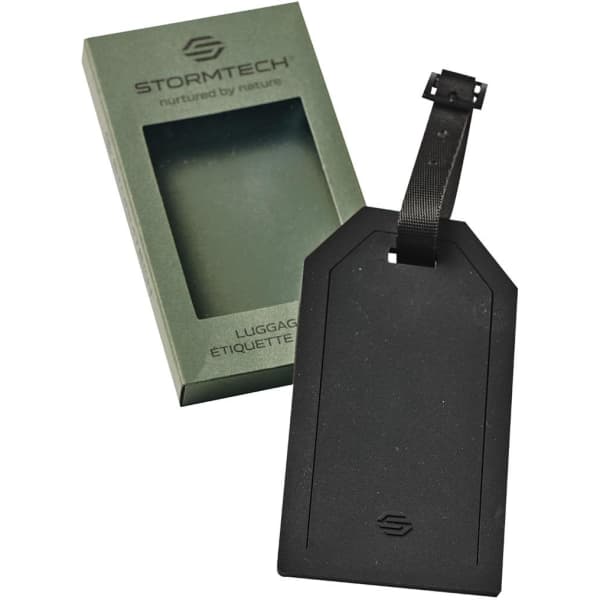 A black luggage tag with a textured surface, packaged in a green box, featuring a logo.