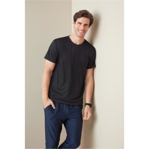 A black men's active cotton touch t-shirt, worn by a smiling man, paired with navy pants, against a light background.