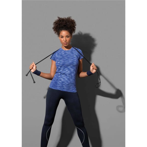A woman demonstrates a blue active seamless raglan t-shirt paired with black leggings, holding exercise ropes.