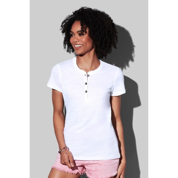 A white women's Henley T-shirt featuring a button-up collar, worn with light pink shorts. The shirt has a logo.