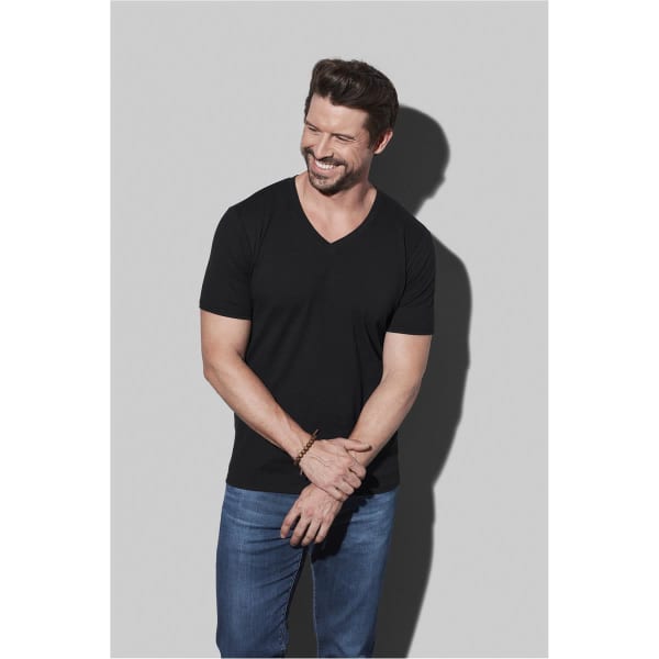 A black men's deep V-neck t-shirt displayed on a model, paired with blue jeans and featuring a logo.