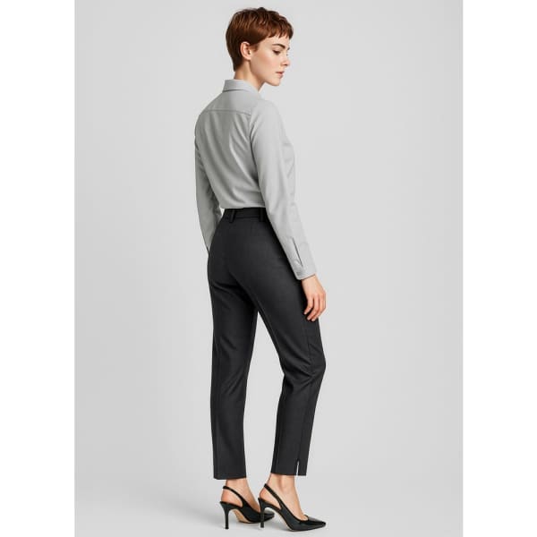 A slim leg pant in dark grey, featuring a sleek design and a logo. Styled with a button-up shirt and high heels.