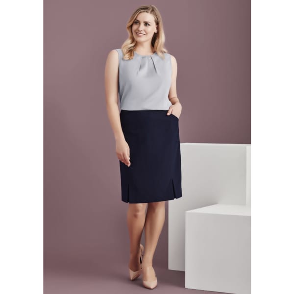A straight skirt in navy blue featuring front pleat details and pockets, styled with a light grey top.