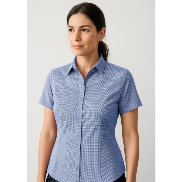 A women's short sleeve button-up shirt in light blue with a subtle check pattern. Features a collar and buttons.