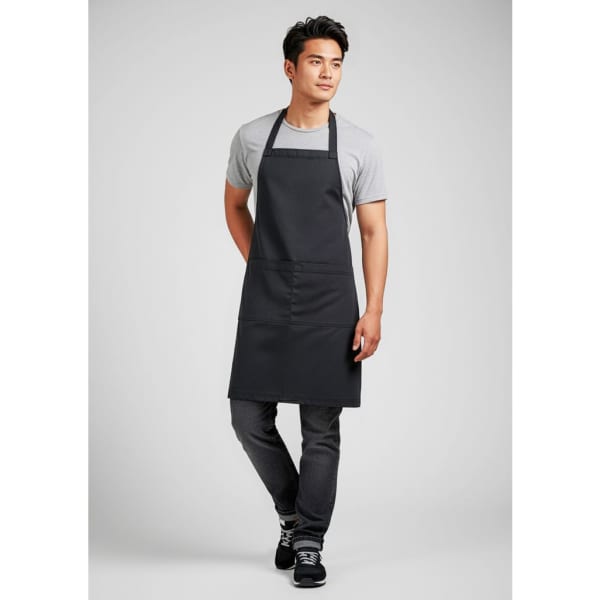A black apron worn by a model, featuring a simple design with adjustable straps and a front pocket.