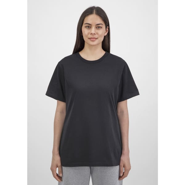 A black women's short sleeve tee is displayed on a model, featuring a simple design and relaxed fit.